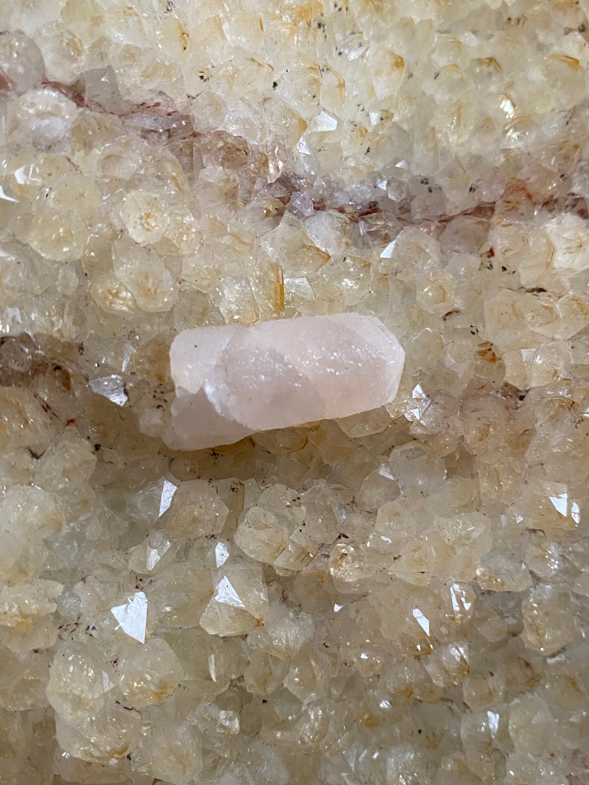 upclose calcite wand within citrine quartz, opaque with milky pink hue.